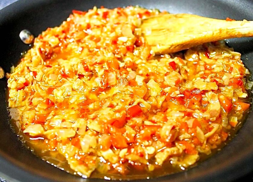 Sofrito en un sartén con una cuchara de madera.