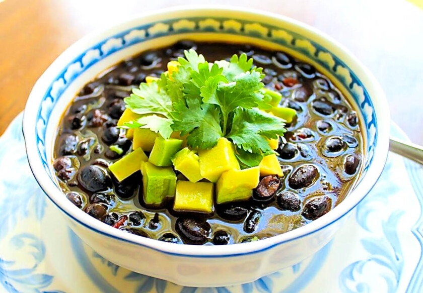 Bol de sopa de caraotas negras con un topping de aguacate con cilantro.