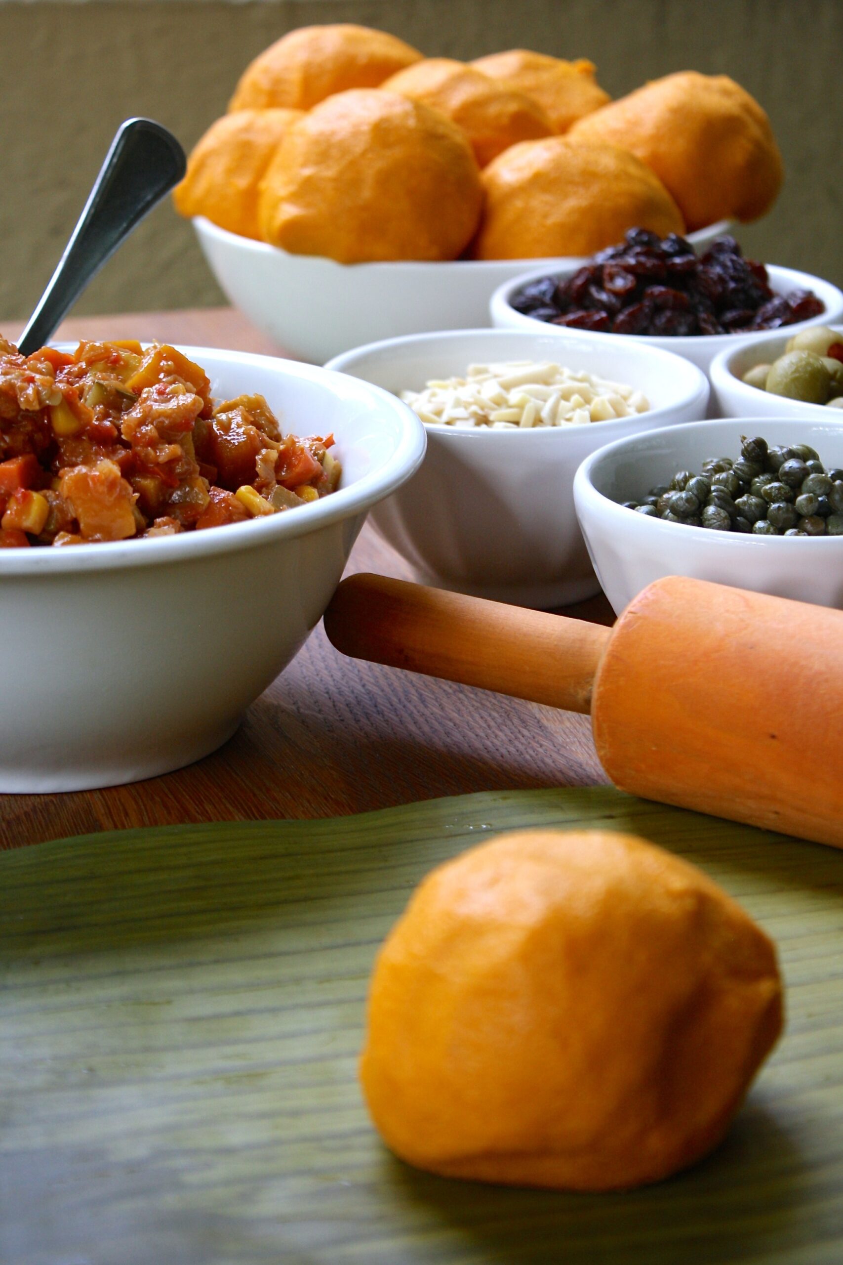 A ball of hallacas dough aver a plantain leaf, plus all the ingredients for the vegetarian hallaca making.
