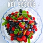 Una Pavlova de frutas del bosque cubierta con varias bayas rojas y azules, adornada con hojas de menta, en un plato decorativo. El texto superpuesto dice "Pavlova de Frutos del Bosque" y "Un postre para impresionar".