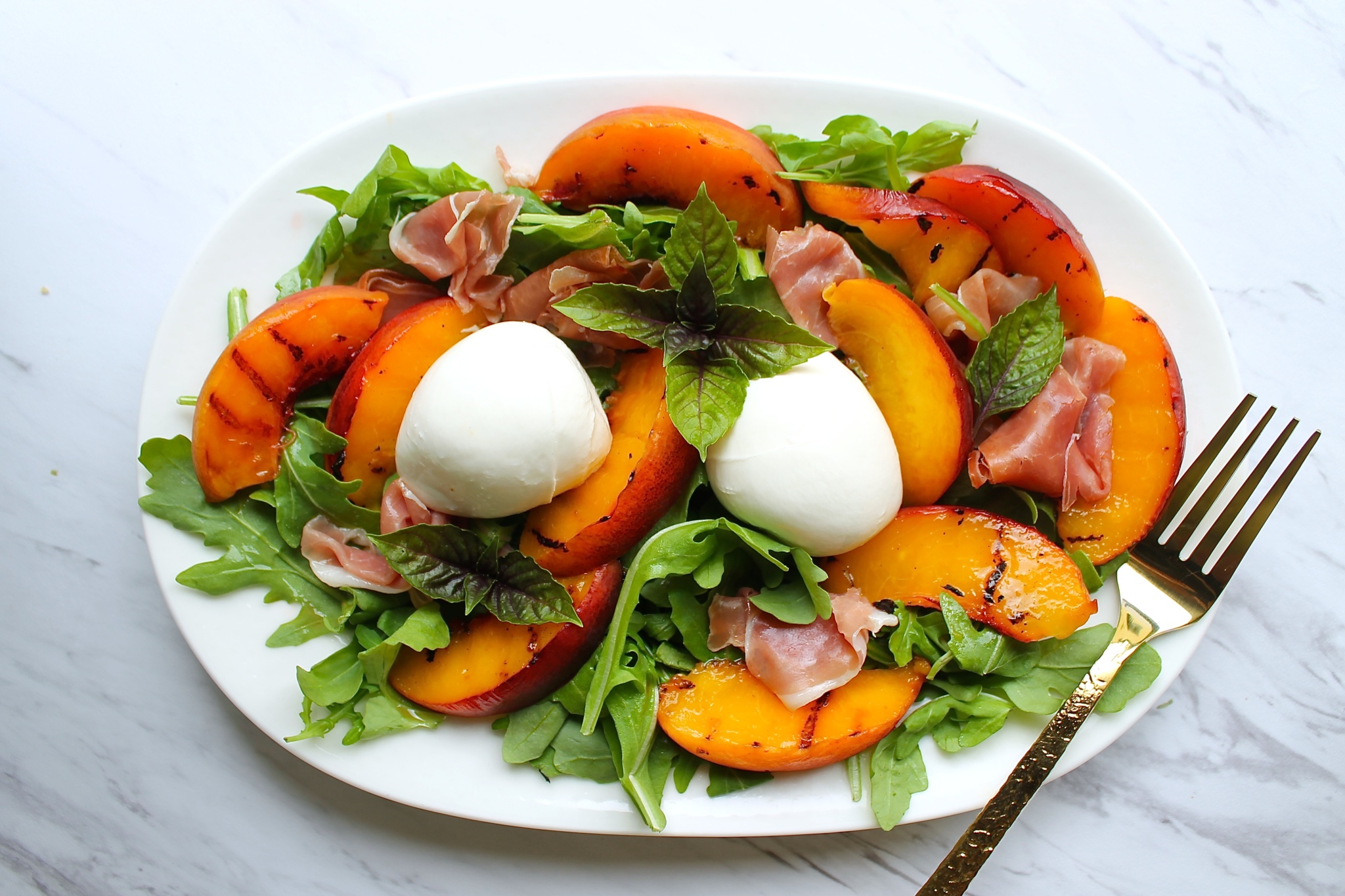 Ensalada de burrata con melocotones, arugula y prosciutto