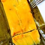 Una hallaca caraqueña de cochino, servida sobre unna hoja de plátano on un tenedor.