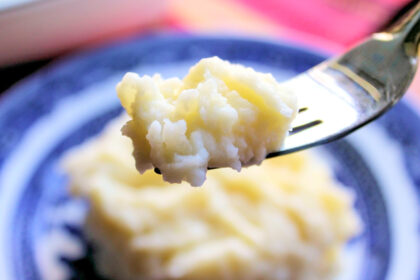 A bite of garlic-infused mashed potatoes on a fork.