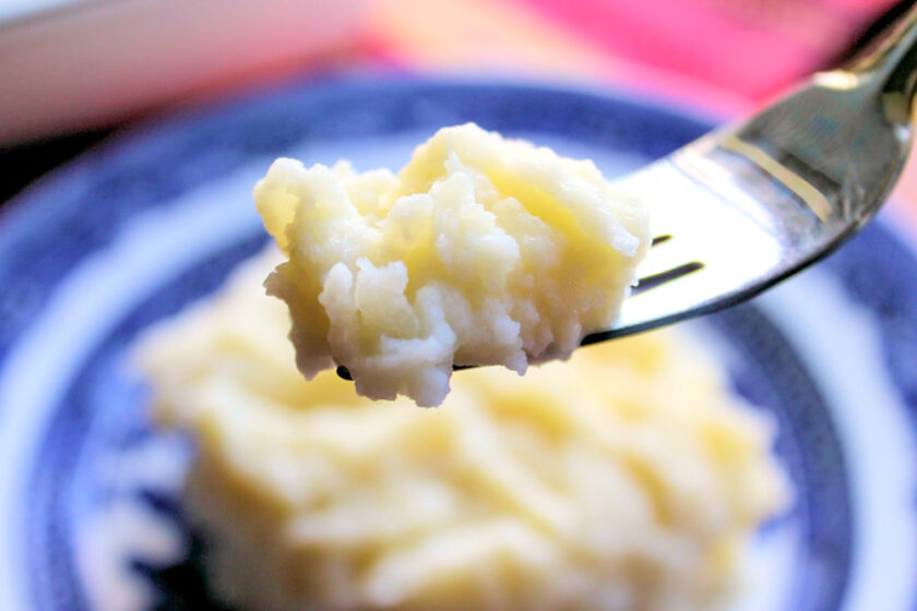 A bite of garlic-infused mashed potatoes on a fork.