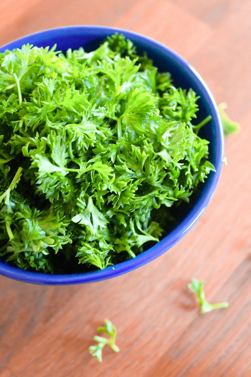 Blue bowls full pf chopped fresh curly parsley.