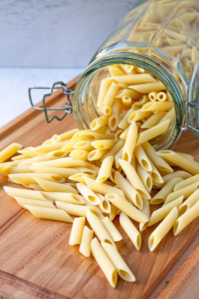 Penne noodles spread in a wooden board.