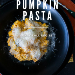 Creamy pumpkin pasta on a black plate.