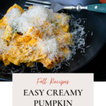 Creamy pumpkin pasta on a black plate.