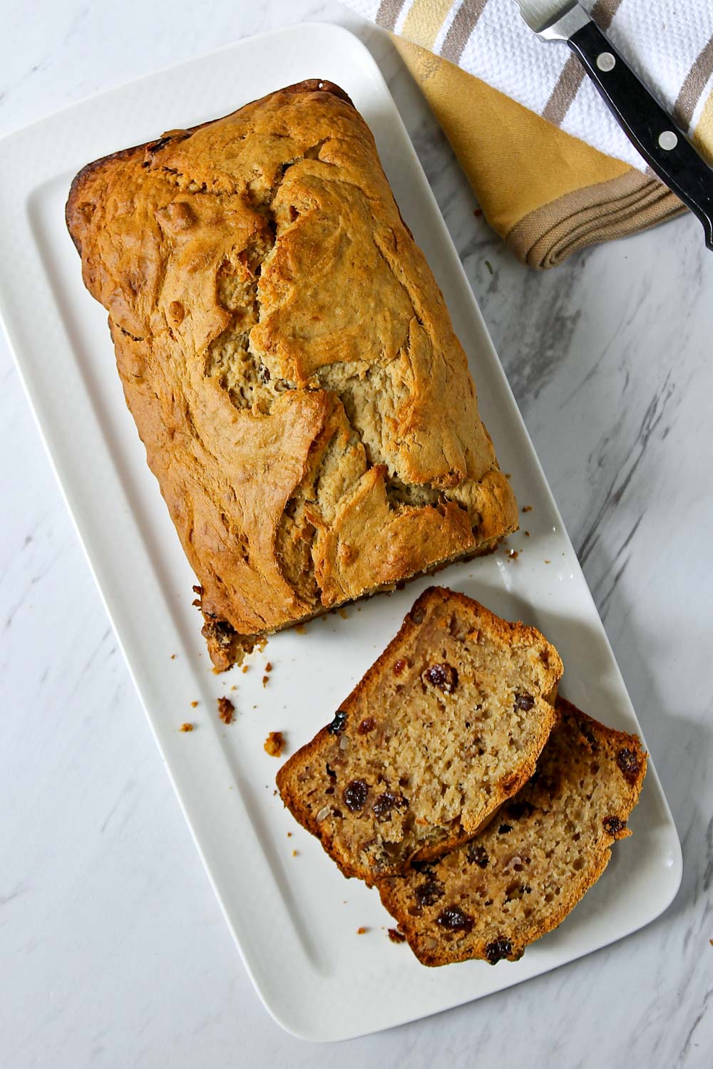Pan de plátano, servido en un plato rectangular, con algunas rebanas cortadas.