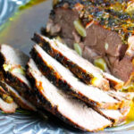 An easy roasted leg of lamb recipe served on a silver plate.