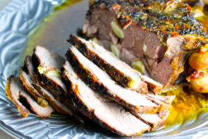 Pierna de cordero asada servida en plato de plata.
