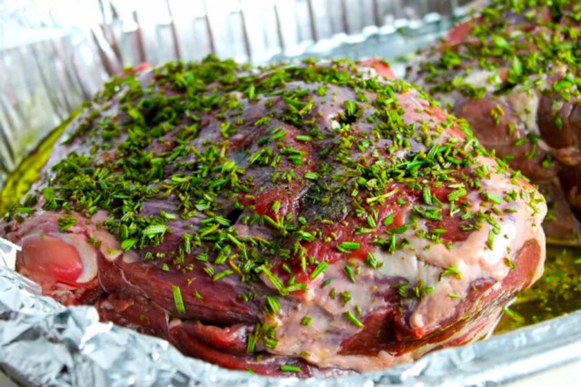 Fresh chopped rosemary crust over a leg of lamb, ready to be roasted in the oven.