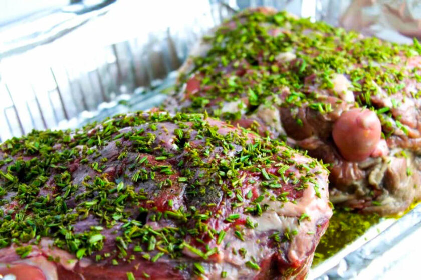 Fresh chopped rosemary crust over a leg of lamb, ready to be roasted in the oven.