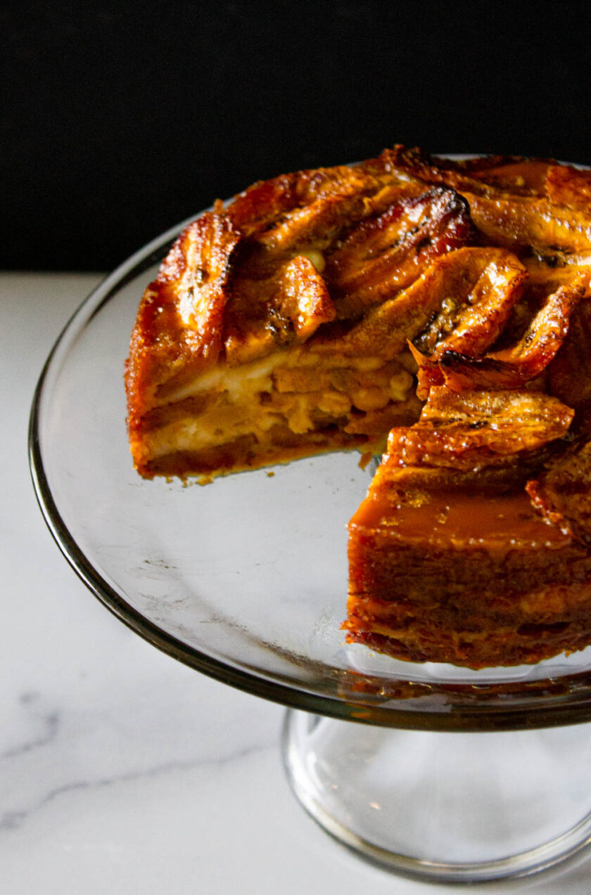 Venezuelan torta de plátano, already sliced, and served in a crystal cake dish.