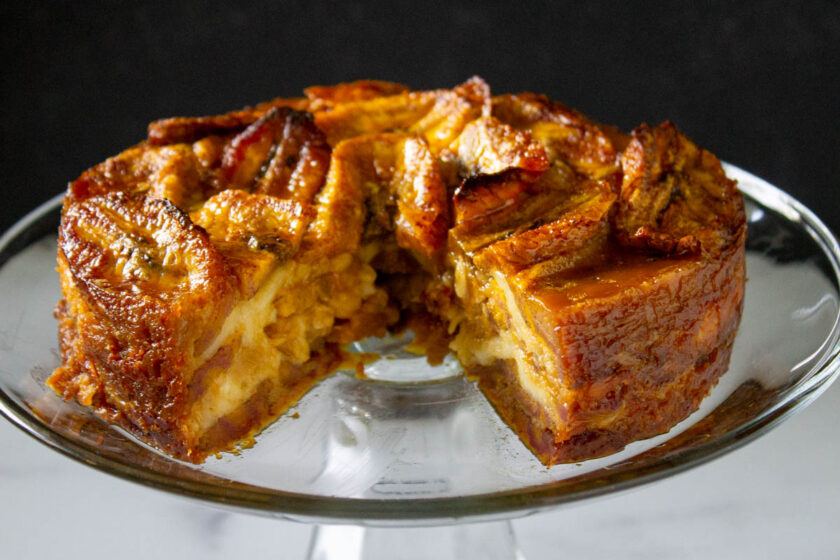 Front view of a Venezuelan torta de plátano with cheese, already sliced and served in a glass platter.