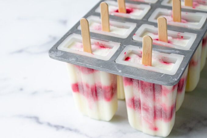 Primer plano de helados de palito de yogur con frambuesa y limón recién salidas del congelador. todavía en los moldes.