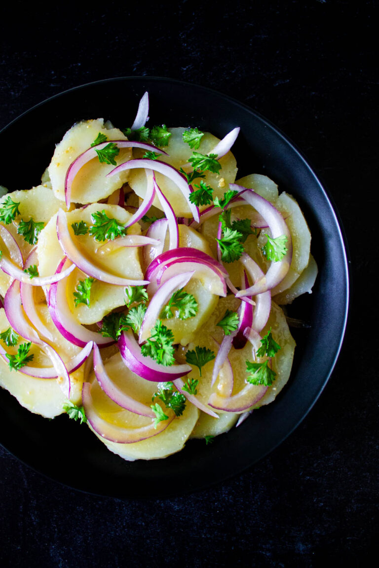 Ensalada venezolana de papas, servida en un plato negro, by enrilemoine.