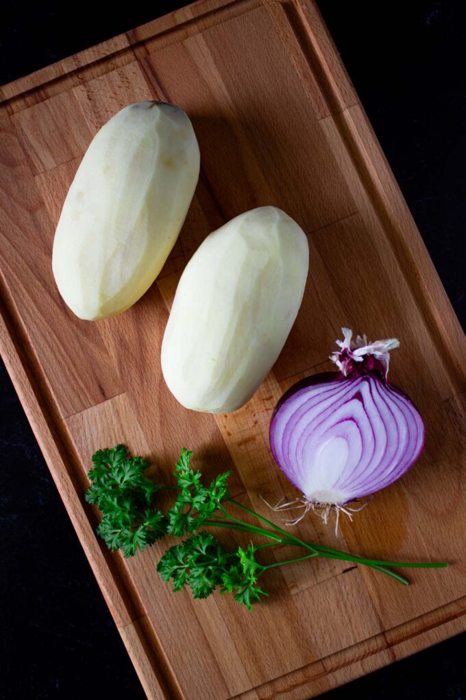 Ingredients to make Venezuelan potato salad, including: peeled potatoes, red onion, and parsley, by enrilemoine.