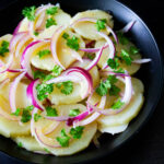 Ensalada de papa venezolana, servida en un plato negro, by enrilemoine.