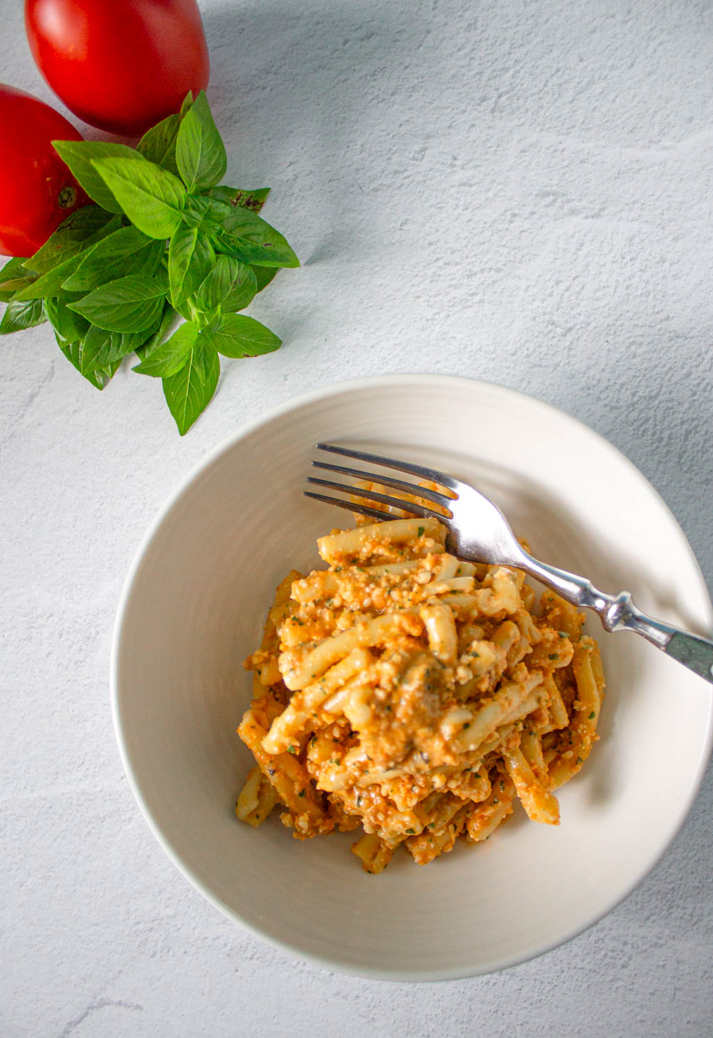 Vista cenital de un tazón blanco con pasta casarecce con Pesto alla Trapanese, by enrilemoine.