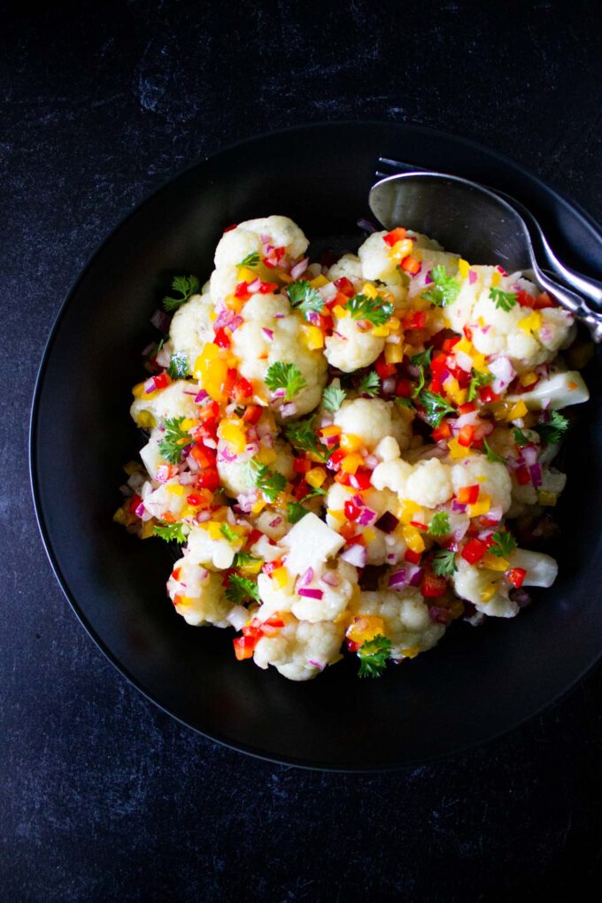 Venezuelan cauliflower salad, served in a black bowl, byenrilemoine.