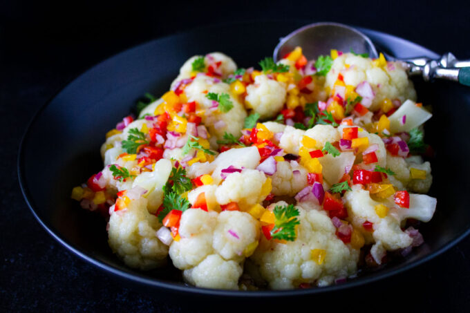 Venezuelan cauliflower salad in a black dish, byenrilemoine.