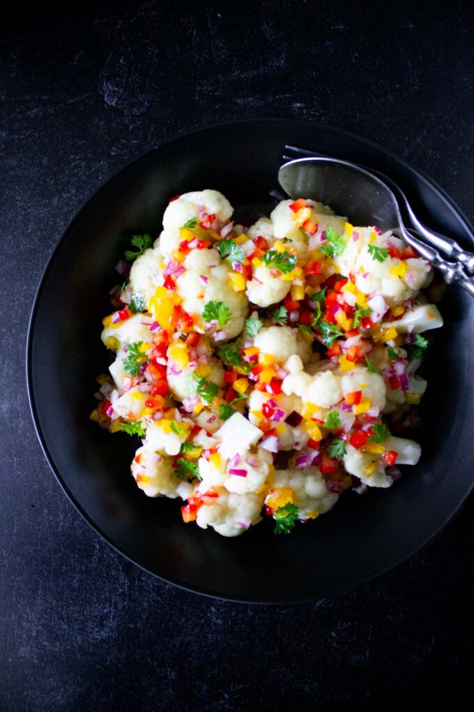 Venezuelan cauliflower salad served on a black bowl, byenrilemoine.