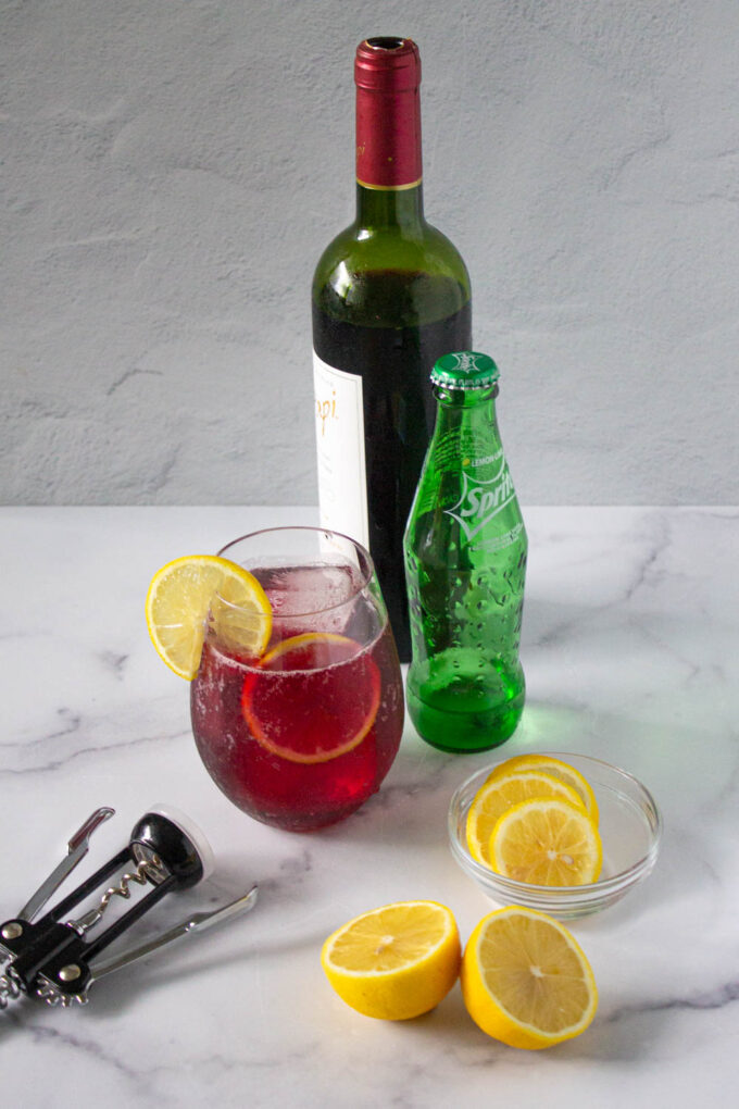 A glass of refreshing Tinto de Verano, a Spanish summer red wine cocktail, plus all the ingredients to make this cocktail, by enrilemoine.
