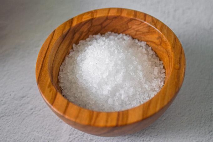 Coarse sea salt on a wooden bowl, by enrilemoine.
