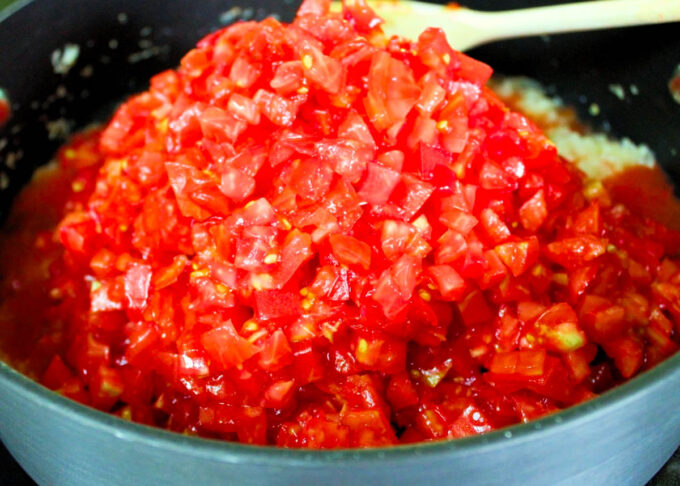 Un sartén con una cuchara de madera y mucho tomate picadito, para hacer sofrioto, by enrilemoine.