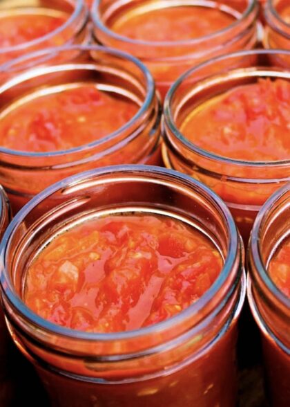 Tomato sauce jars on a wooden table displaying Venezuelan sofrito.