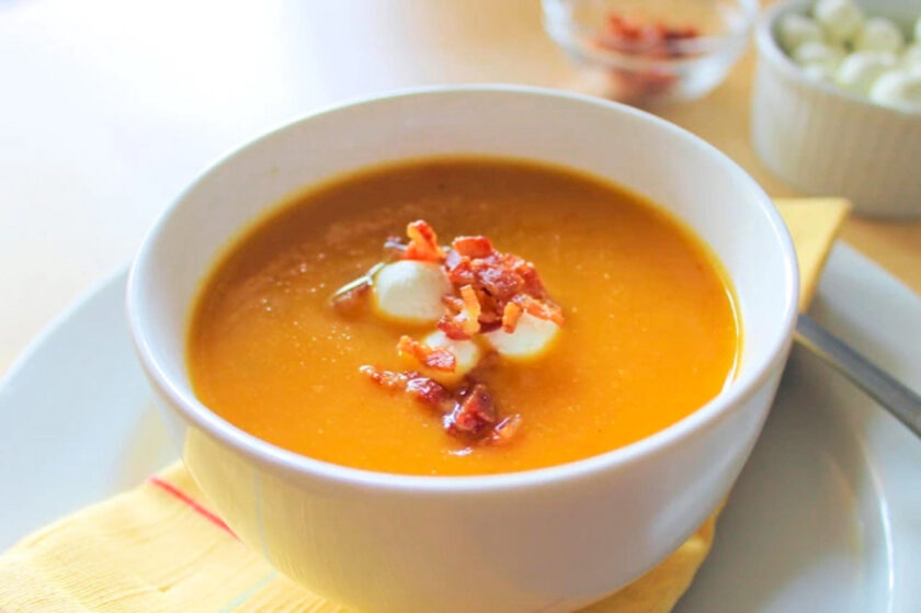 A bowl of roasted veggies soup with bacon on top, by enrilemoine.
