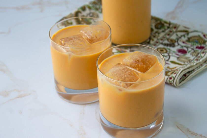 Dos vasos de ponche crema de calabaza con cubitos de hielo.