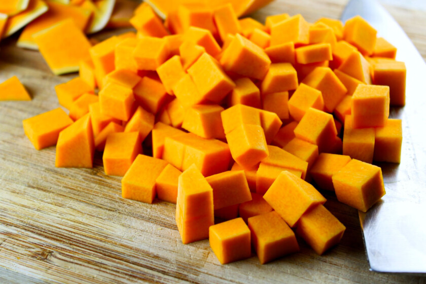 Cubed butternut squash on a cutting board next to a knife.