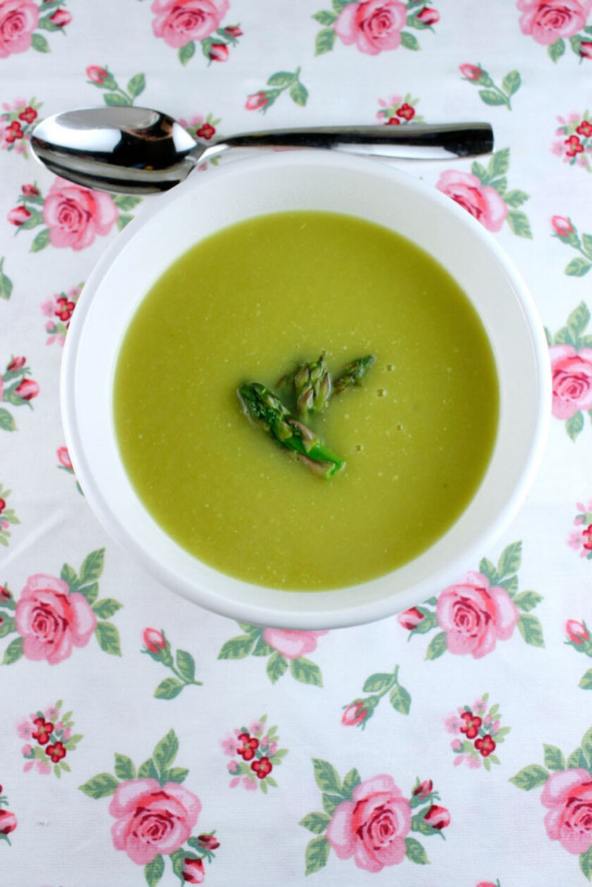 A cozy bowl of asparagus soup , placed on a pink tablecloth.