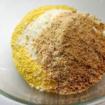 Harina de maiz, queso blanco rallado y papelón rallado en un tazón.