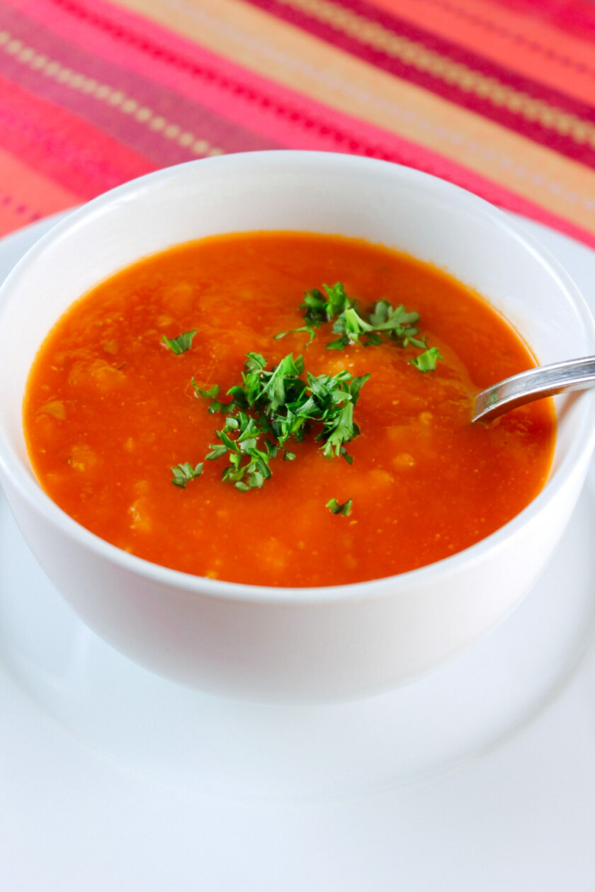 A tomato soup bowl, garnished with parsley.