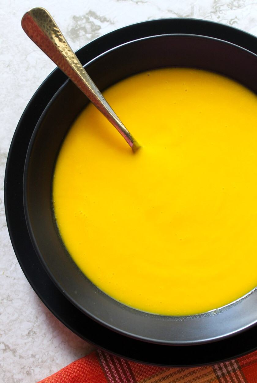 Butternut squash soup served on a black bowl.