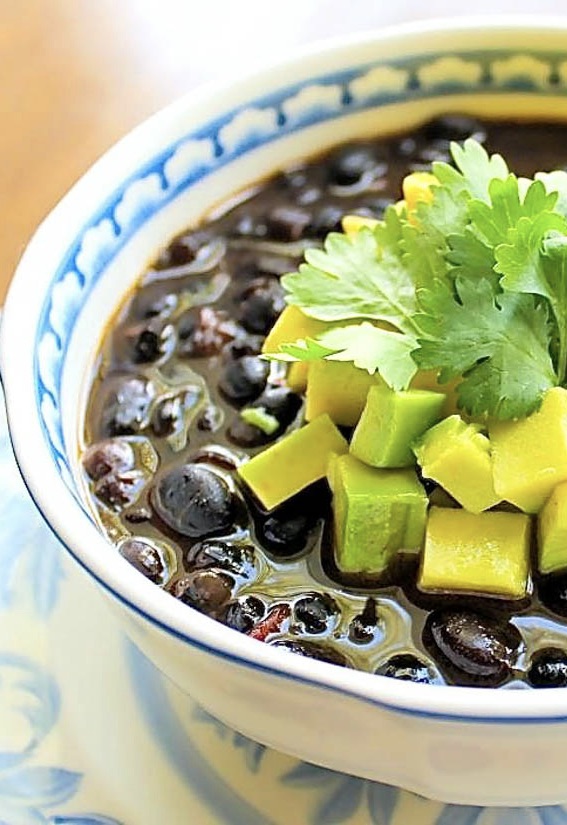 A bowl of Venezuelan black beans soup garnished with avocado and cilantro.