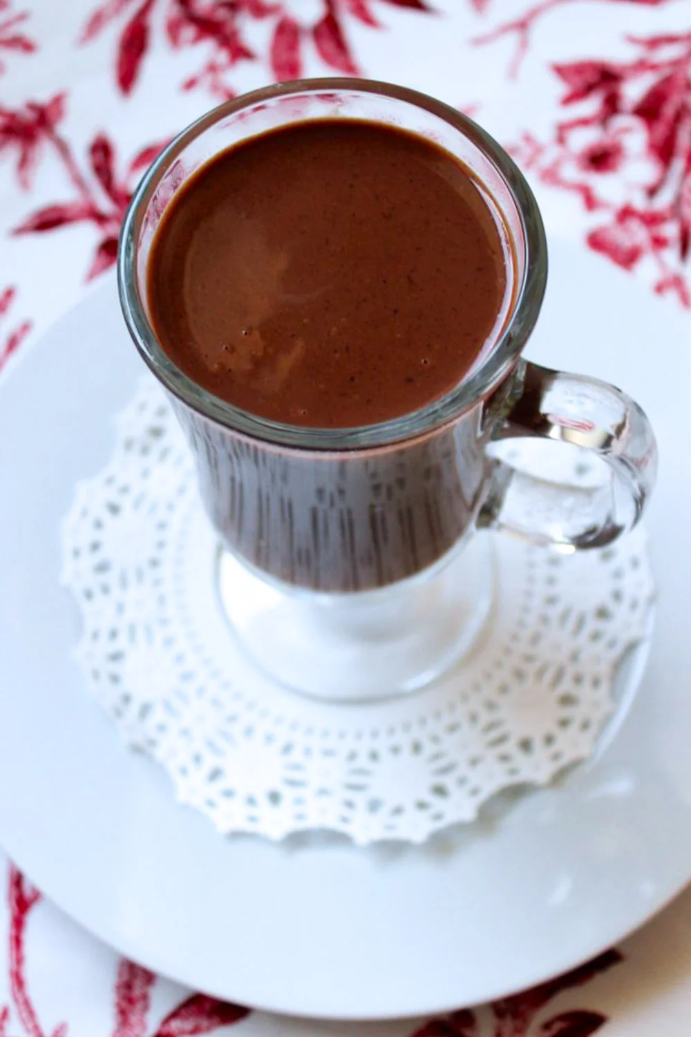 Una taza de chocolate caliente sobre un plato con una blonda.
