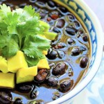 Plato de sopa de caraotas negras con aguacate y cilantro.