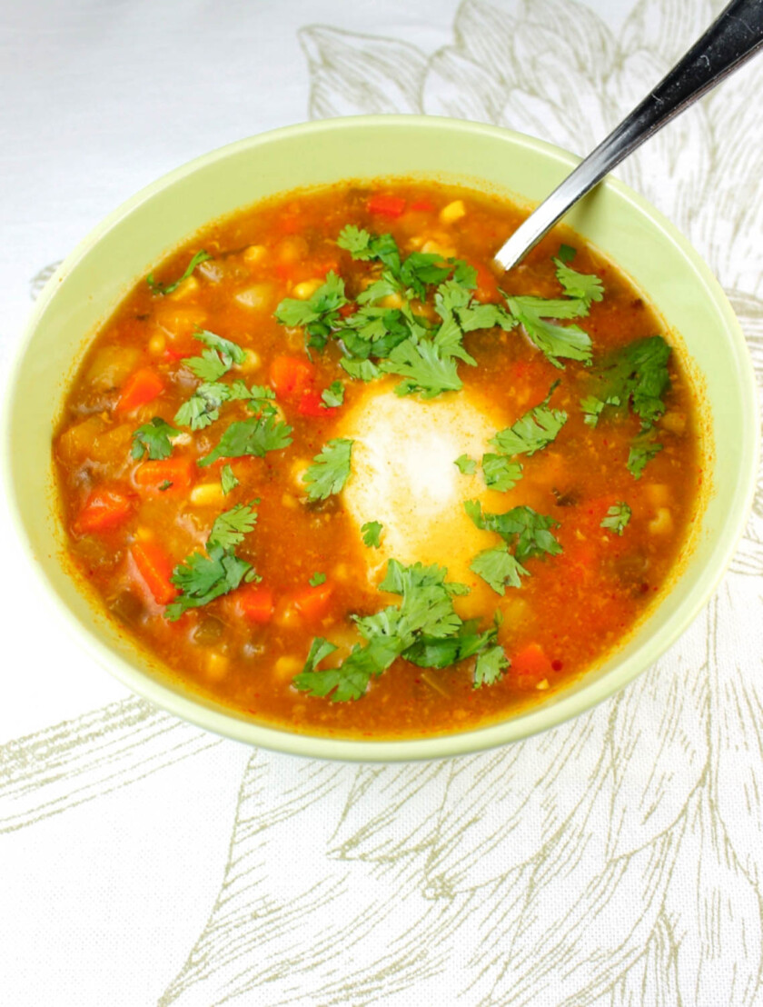 A bowl of veggie soup with and egg.