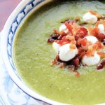 A bowlof zucchini soup with goat cheese and bacon bites.