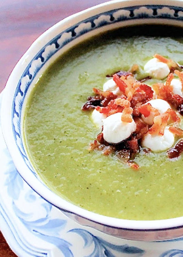 A bowlof zucchini soup with goat cheese and bacon bites.