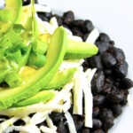 A plate with black beans, white cheese, and avocado on it.