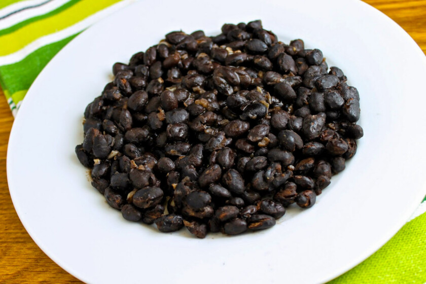 Un plato blanco con caraotas negras refritas.