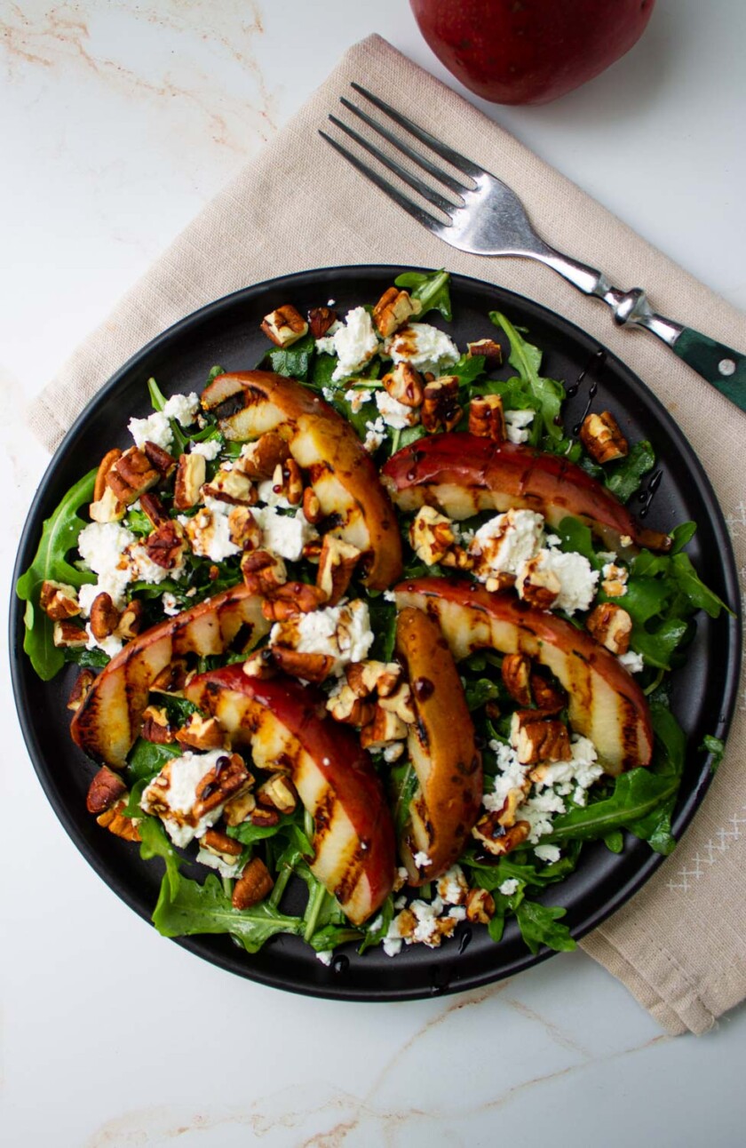 A plate of salad with grilled pears and cheese.