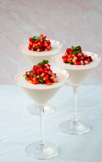 Tres panna cottas de fresa servidas en copas de martini.