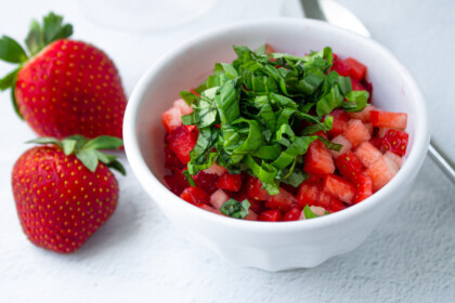 Diced strawberries with chopped basiol on a white bowl.