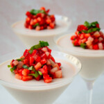 Tres copas de martini con panna cotta de fresas, decoradas con fresas picaditas y albahaca.